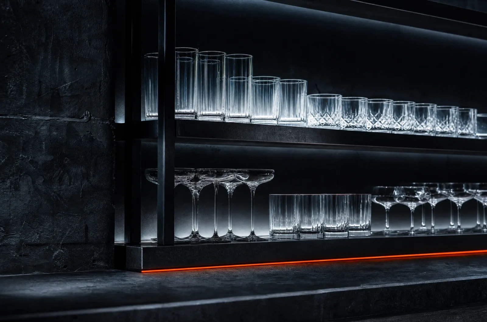A steel shelf with rows of empty glassware, backlit