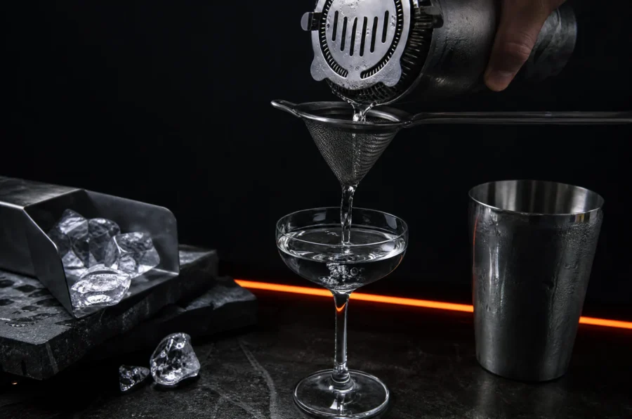 A Hawthorne strainer and fine mesh cone above a coupe glass